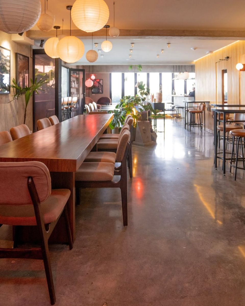 Mesa larga y mesas altas junto a la pared de madera